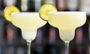 Två frostiga margaritas med saltkant och limeklyfta, redo att avnjutas.