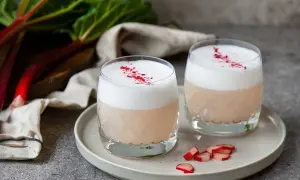 Två glas med rabarber sour, toppade med skum och strödd rabarberpulver. En härlig syrlig sommardröm.