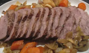 Skivad kalvstek i ugn serverad med rotfrukter och lök. En härlig middag!