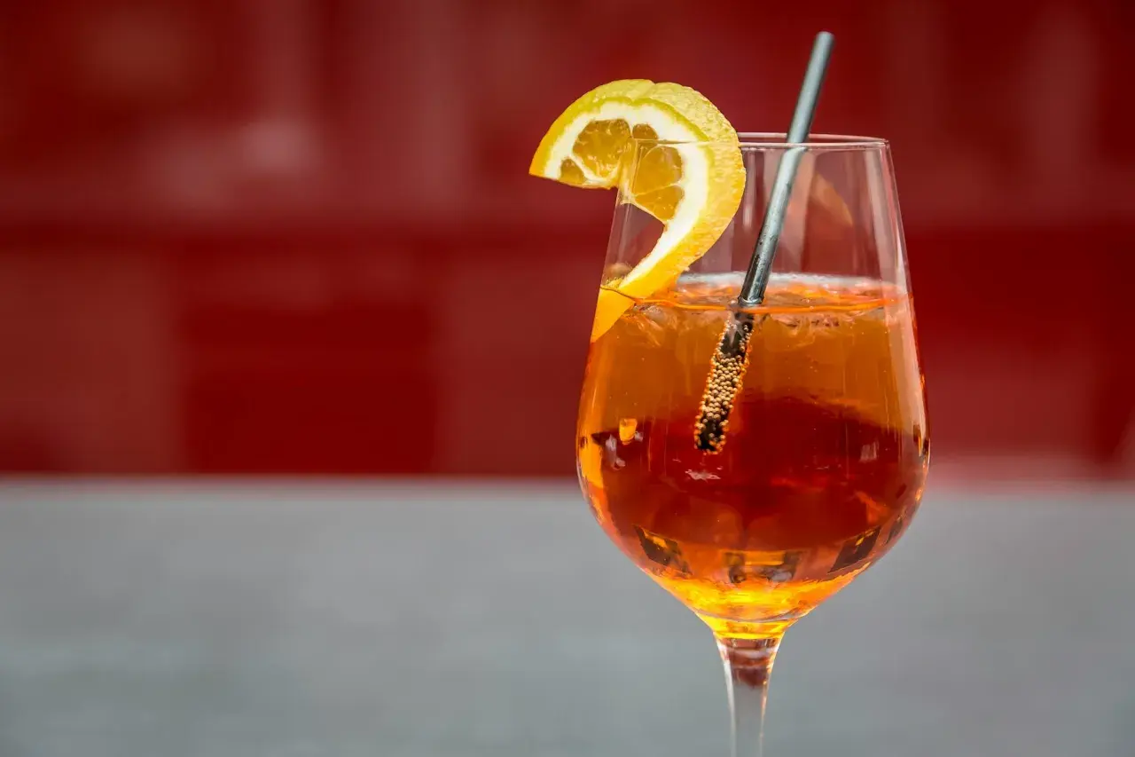 Ett glas Aperol Spritz med en apelsinskiva och sugrör, redo att avnjutas.