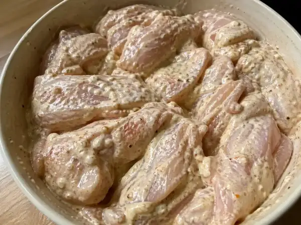 Rå kycklingbitar i en krämig marinad. Denna yoghurtmarinerade kyckling ser ut att bli otroligt saftig och smakrik.