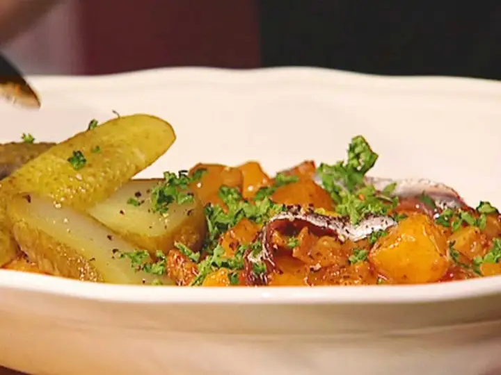 En portion pytt Bellman med stekt potatis, inlagd gurka och ansjovis, toppad med persilja.