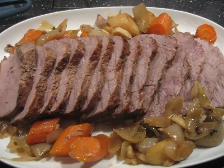 Skivad kalvstek i ugn serverad med rotfrukter och lök. En härlig middag!